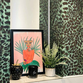 A painting of a fun leopard character dressed in orange and green, placed in an alcove surrounded by green leopard print wallpaper