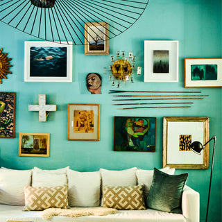 A beautiful blue gallery wall with pictures in different frames.