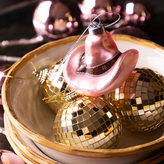 Image of a bowl filled with small gold disco ball baubles with a cowgirl hat christmas tree decoration placed on  top.