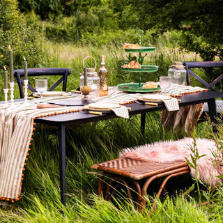 a black garden table in a natural setting with pink and green accessories 