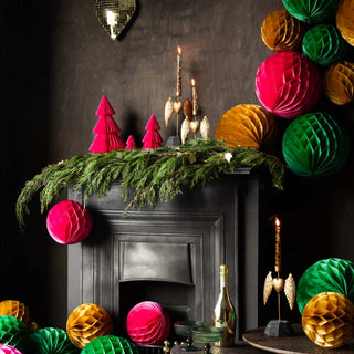 A display of green, gold and pink honeycomb ball Christmas decorations over a fireplace. 