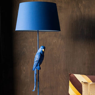 A large royal blue floor lamp with a fake blue parrot on it.