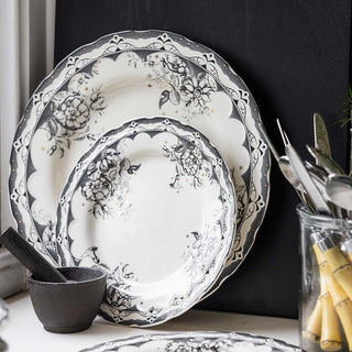 Black and white dinner plates set on a festive table with napkins, crackers and christmas centrepiece accessories.