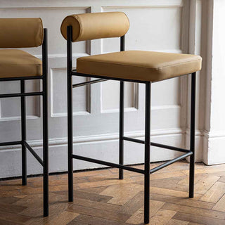 Two green bar stools styled in a kitchen next to a kitchen island.