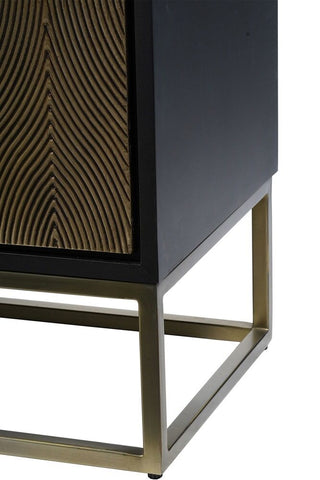 Corner detailing of a black cabinet with gold inlay and a brass frame