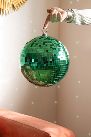 The Green Disco Ball being held by a model, reflecting light into the room behind.