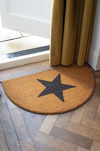 The Half Moon Star Doormat styled in a doorway with a door curtain in the background.