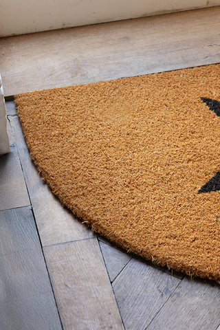 Detail shot of the Half Moon Star Doormat on a wooden floor.