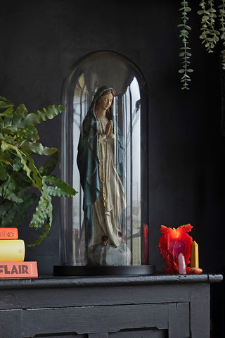 The Large Glass Dome Ornament with a statue inside, styled on a black sideboard with books, a plant, crystals and a lit candle.