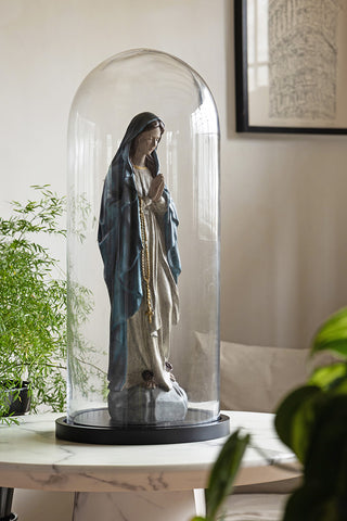 The Large Glass Dome Ornament with a statue inside, styled on a table surrounded by plants.