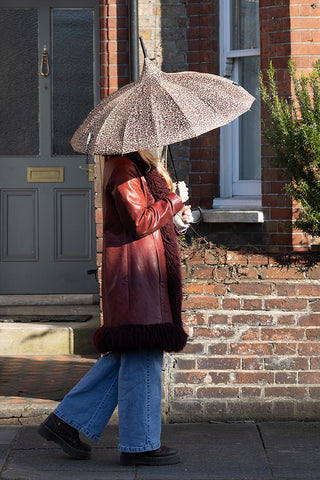 Lifestyle image of the Leopard Print Umbrella being held outside a town house.