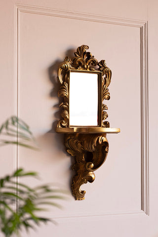 The Ornamental Wall Shelf with Mirror styled on the wall, with a plant in the corner of the shot.