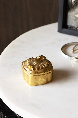 The Ornate Sacred Heart Trinket Box styled on a white marble surface with some accessories in the background.