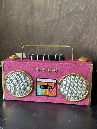 The pink boom box decoration on a sideboard. The decoration shows sign of ware, with slight dents and glue imperfections.