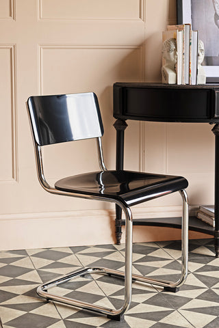 The Retro Inspired Curved Dining Chair in Black styled next to a console table.