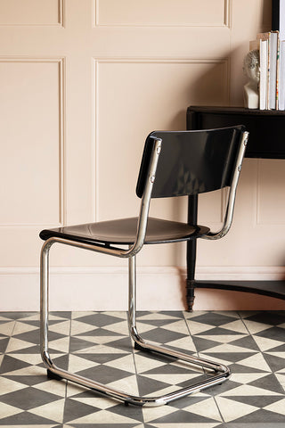 The Retro Inspired Curved Dining Chair in Black seen from the back, styled in front of a console table.