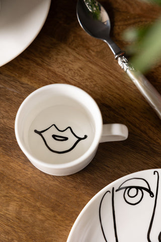 The Female Face Coffee Cup seen from above, styled on a wooden table.