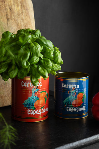 The Set Of 2 Flamenco & Orange Kitchen Storage Tins on a dark surface, styled with a herb plant, greenery and a wooden chopping board.