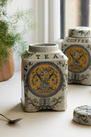 The Tea Storage Jar from the Set of 2 Ceramic Tea & Coffee Storage Jars, with the lid off, styled with a spoon, plant, wooden board and the Coffee version in the background.