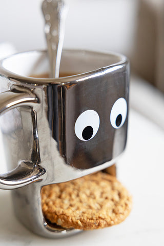 Close-up of the silver face mug with a slot for a biscuit.