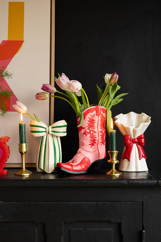 The White & Green Beautiful Bow Bud Vase styled on a black sideboard with another bow vase and a cowboy boot vase, with some tulips, lit candles and a large art print.