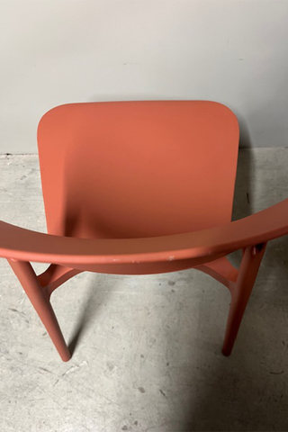 Birdseye view of the chair seat showing the scratched chair back of the burnt orange plastic chair.