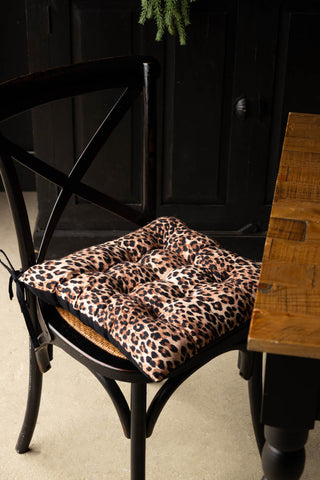 The Leopard Print Seat Cushion styled on a chair next to a dining table.