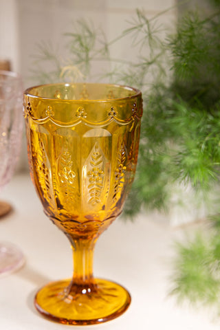 Close-up of one of the Set of 6 Colourful Vintage-Style Wine Glasses, styled with a plant in the background.