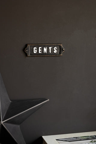 The Gents Door Hanging Sign displayed on a black wall above a star ornament.