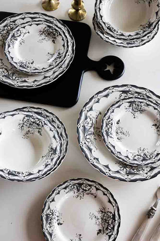 The 12-Piece Vintage-Style Floral & Star Dinner Set displayed on a white surface with a black serving board, cutlery and two gold candlestick holders.