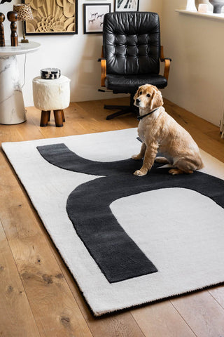 The Abstract Canvas Rug styled in a living room with a dog sitting on it.