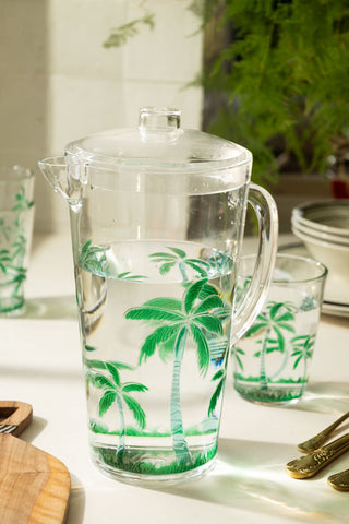 A lifestyle image of a clear acrylic picnic jug with green palm trees on it.