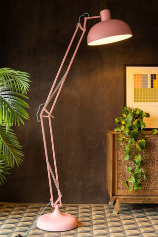 The Adjustable Pink Task Floor Lamp with Blue Flex switched on and styled with some plants, a leopard print sideboard and an an art print.