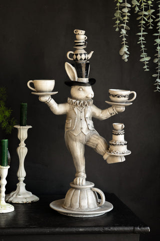 An incredibly quirky ornament bursting with personality. The quirky ornament is of a white alice in wonderland rabbit balancing tea cups in its hands, head and legs.