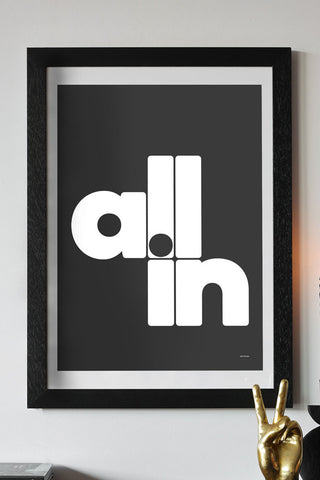 The All In Black & White Art Print - Unframed styled in a black frame on a white wall, above a gold peace hand ornament.