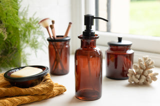 Beautiful amber glass apothecary-style bathroom set on a bathroom window sill.