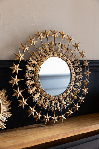 Lifestyle image of the Antique Gold Jewelled Star Wall Mirror styled on a shelf