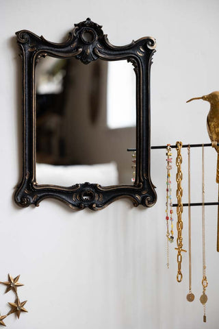 The Antique-Inspired Black Framed Mirror on the wall, styled next to some jewellery on a stand and a star ornament.