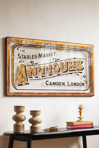 The Antique-Style Gold Framed Stables Market Wall Art styled on a white wall above a table with various accessories on.