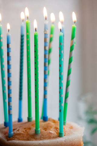 Close-up of the Assorted Blue Cake Candles - Pack Of 10, lit and displayed in a cake.