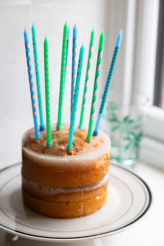 The Assorted Blue Cake Candles - Pack Of 10 styled in a cake, displayed on a black and white plate.