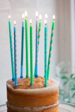 The Assorted Blue Cake Candles - Pack Of 10 lit and displayed in a cake.