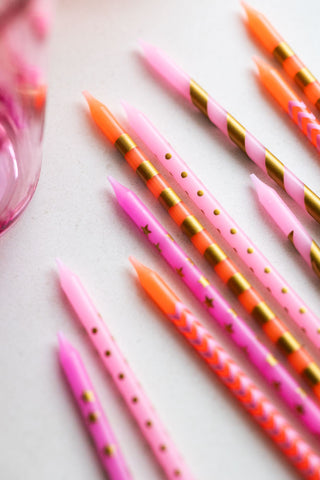 Close-up of the Assorted Pink Cake Candles - Pack Of 10 laying on a neutral surface.