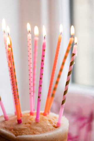 Detail shot of the lit Assorted Pink Cake Candles - Pack Of 10 styled in the top of a cake.