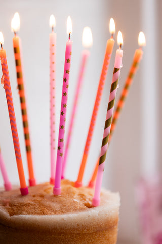 The Assorted Pink Cake Candles - Pack Of 10 lit and styled in a cake.