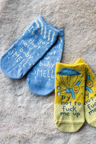 The New Baby Smell Baby Socks displayed together on a grey fluffy background.