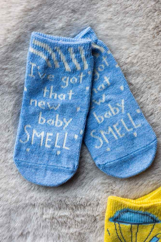 The New Baby Smell Baby Socks on a grey fluffy background.