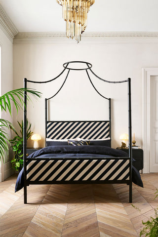 Lifestyle image of the Bamboo Bed straight on against a light wall in a bedroom.