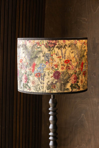 The Bamboo Floral Print Easyfit Lampshade styled on a floor lamp in front of a dark wall.