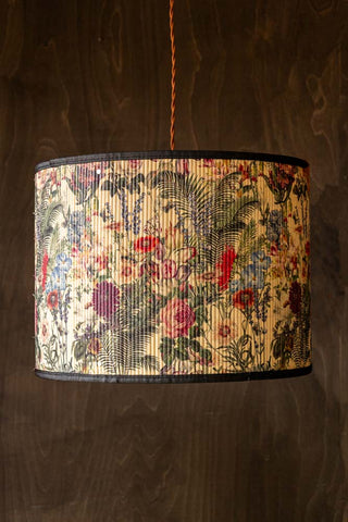 The Bamboo Floral Print Easyfit Lampshade styled as a pendant shade in front of a dark wall.